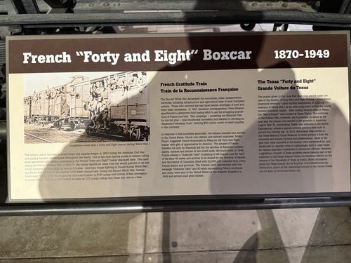 A long horizontal interpretive panel titled 'French "Forty and Eight" Boxcar 1870-1949' mounted on a rail in front of the boxcar. It has an archival photo of doughboys riding in a Forty and Eight car and three text sections: a main history column, 'French Gratitude Train / Train de la Reconnaissance Francaise', and 'The Texas "Forty and Eight" / Grande Voiture du Texas'.