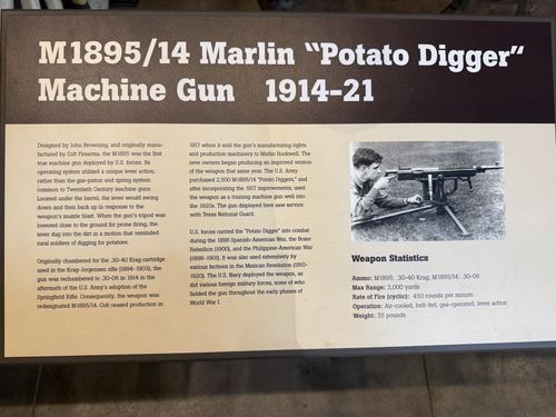 An angled close-up of the placard for the M1895/14 Marlin 'Potato Digger' Machine Gun, with a black-and-white photo of a soldier firing it and a Weapon Statistics box. Mostly legible.