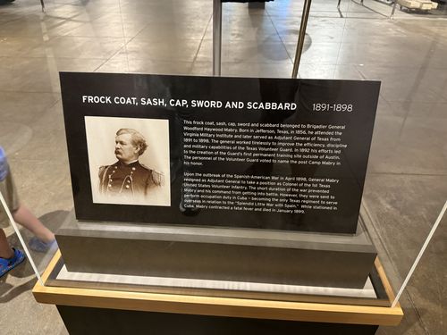 A black case-front placard titled 'Frock Coat, Sash, Cap, Sword and Scabbard 1891-1898' with a portrait photo of Brigadier General Woodford Haywood Mabry and two paragraphs of text.