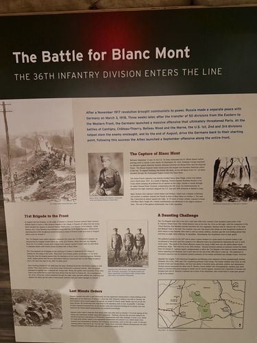 Wall panel titled 'The Battle for Blanc Mont - The 36th Infantry Division Enters the Line', with a portrait of Major General John Lejeune, combat photos, a map of France, and sections headed 'The Capture of Blanc Mont', '71st Brigade to the Front', 'A Daunting Challenge', and 'Last Minute Orders'.