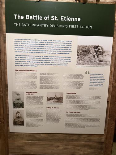 Large story panel titled 'The Battle of St. Etienne - The 36th Infantry Division's First Action,' with sections 'The Bloody Eighth of October,' 'Medals of Honor on Hill 160,' 'Taking St. Etienne,' 'Counterattack,' and 'Day Two of the Battle,' plus portraits and a battlefield photo.