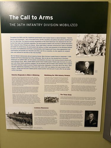 Large wall interpretive panel titled 'The Call to Arms – The 36th Infantry Division Mobilized', with cream background and several sub-sections of text plus period photos (including a portrait identified as President Franklin D. Roosevelt and a general's portrait). Covers the rise of fascism/Nazism/communism in the 1920s-30s, the outbreak of WWII, and the mobilization of the 36th Infantry Division. Some lower text is partly obscured by glare/angle.