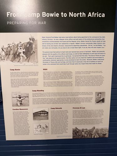 Large wall interpretive panel titled 'From Camp Bowie to North Africa / Preparing for War', with a period photo of soldiers training and several columns of text under subheads (Camp Bowie, WAR!, Carolina Maneuvers, Camp Blanding, Camp Edwards, Overseas At Last).