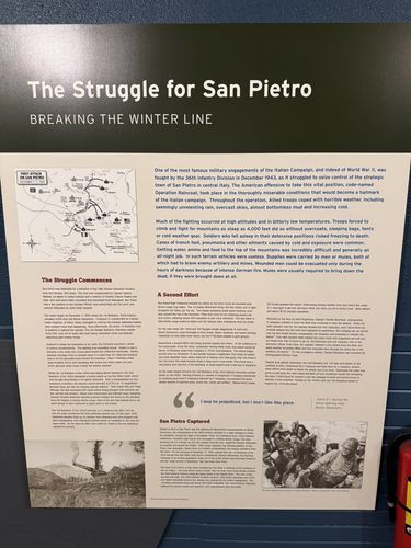 Large wall panel titled 'The Struggle for San Pietro / Breaking the Winter Line', with a map ('First Attack on San Pietro', December 7-11, 1943), a photo, and columns under 'The Struggle Commences', 'A Second Effort', and 'San Pietro Captured'.