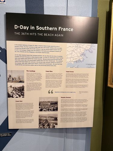Large wall panel titled 'D-Day in Southern France' with photos of landing craft and beach assaults, a map of the Seventh Army landings, and several sub-headed text columns.