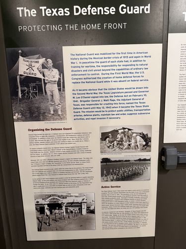 Wall panel titled 'The Texas Defense Guard' with a large photo of a uniformed sergeant in front of a 'TEXAS DEFENSE GUARD 19' flag, plus photos of a women's auxiliary and marching guardsmen, and multiple text columns.