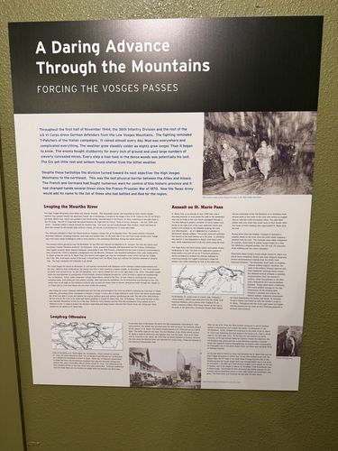 Wall panel titled 'A Daring Advance Through the Mountains' with photos of infantry advancing in wooded mountains, two maps of the St. Marie Pass and Meurthe River area, and several text columns.