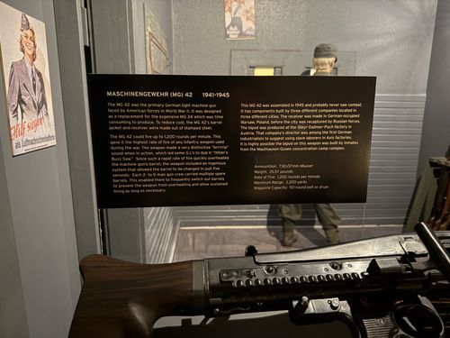 Close-up of the placard for the MG 42 machine gun, titled 'MASCHINENGEWEHR (MG) 42 1941-1945', with the gun's wooden stock visible in the foreground.
