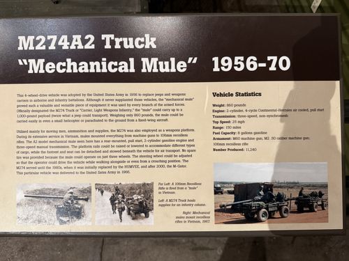 A brown-toned vehicle label titled 'M274A2 Truck "Mechanical Mule" 1956-70', with body text, a 'Vehicle Statistics' box on the right, and three Vietnam-era photos along the bottom showing mules hauling supplies and mounting recoilless rifles.