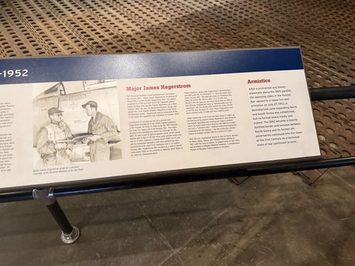Angled shot of the right-hand end of a long Korean War banner placard, showing the 'Major James Hagerstrom' and 'Armistice' sections with a black-and-white photo of two airmen by an aircraft. The header date '-1952' is partly visible at left.