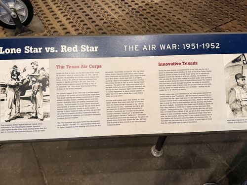 Angled shot of the left-center portion of the same banner placard, headed 'Lone Star vs. Red Star — THE AIR WAR: 1951-1952', with sections 'The Texas Air Corps' and 'Innovative Texans' and black-and-white photos of pilots.