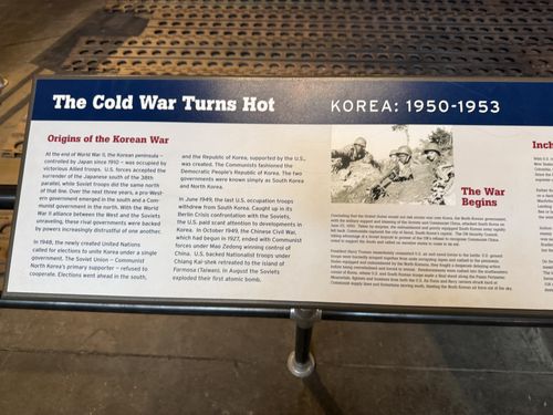 Angled shot of the left end of the same Korea banner, headed 'The Cold War Turns Hot — KOREA: 1950-1953', with the section 'Origins of the Korean War,' 'The War Begins,' and a black-and-white photo of GIs.